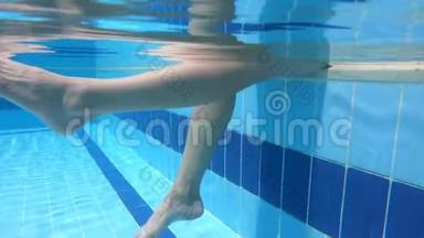 年轻女子的双腿在游泳池中<strong>不褪色</strong>，慢慢地溅起水花